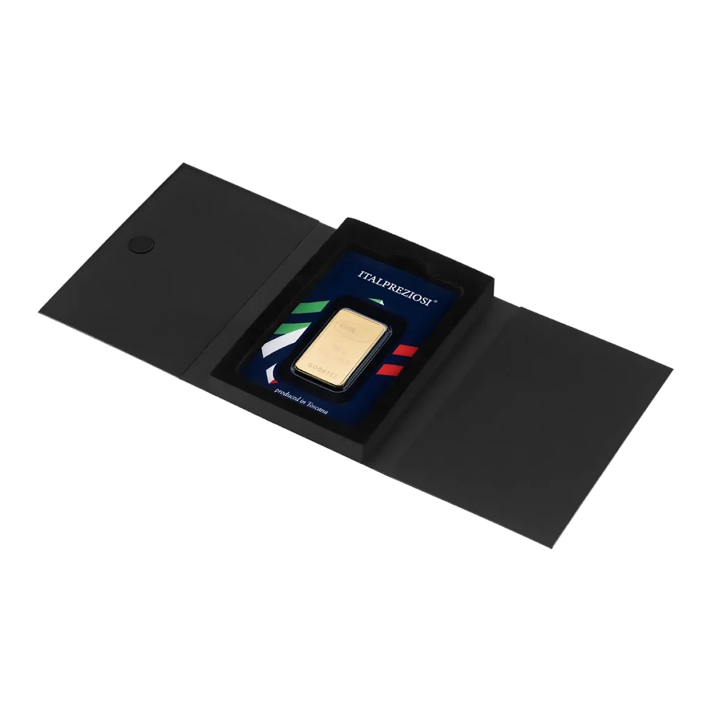 El Lingote de oro 20gr se presenta en un tarjetero negro con funda protectora, dentro de una elegante carpeta negra abierta. La tarjeta muestra rayas de colores además del texto TRAUBERSON y "Orgullosos de proteger".