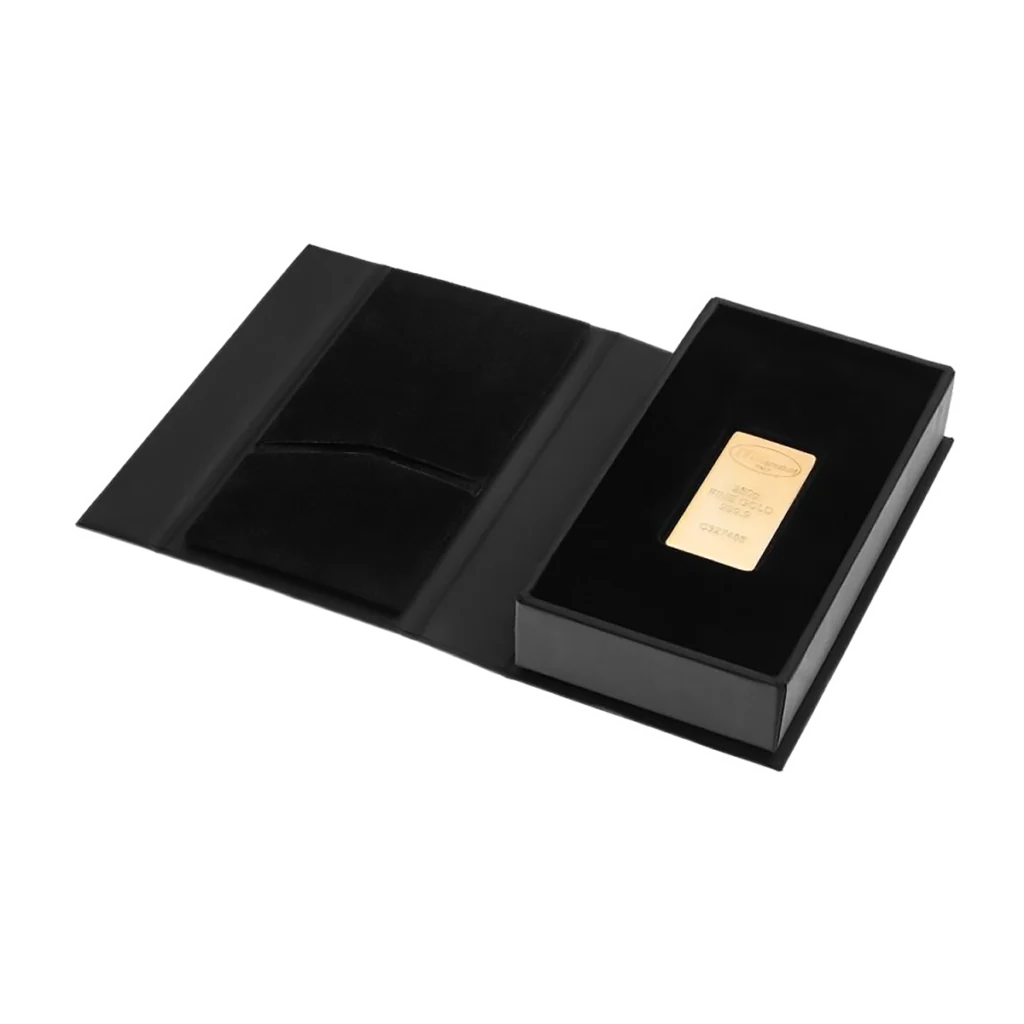 El Lingote de oro 250gr se presenta como un lingote de oro rectangular colocado en una caja de presentación negra abierta con un interior suave y aterciopelado y una solapa en el lado izquierdo.