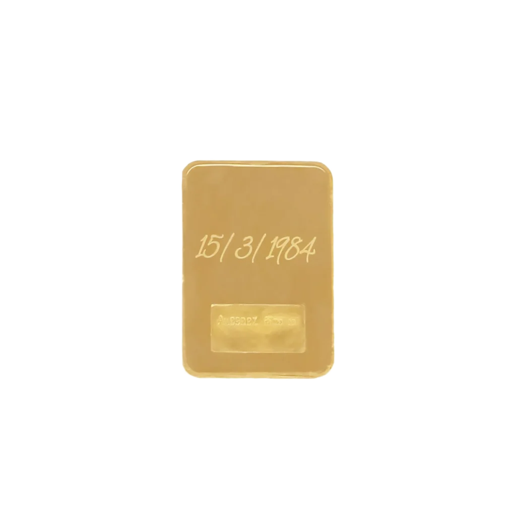 El Lingote de oro 2gr es un lingote rectangular de oro con la fecha 15/3/1984 grabada en la parte superior, sobre un fondo blanco liso.