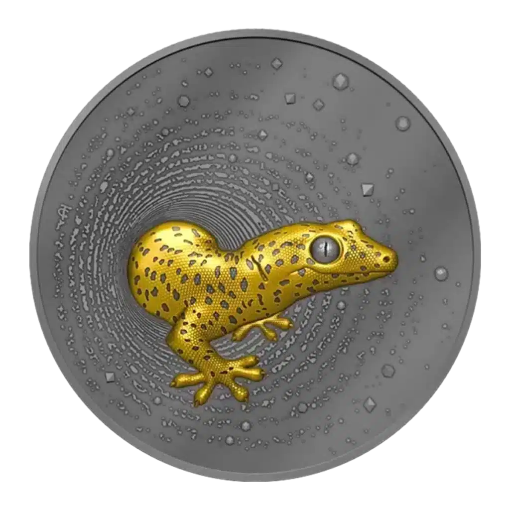 La moneda Camerún 2023 Gecko 2 oz Plata Oscura Dorada UHR muestra en su centro un gecko con manchas amarillas y negras en relieve, con motivos circulares texturizados que irradian sobre el fondo plateado.