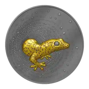 La moneda Camerún 2023 Gecko 2 oz Plata Oscura Dorada UHR muestra en su centro un gecko con manchas amarillas y negras en relieve, con motivos circulares texturizados que irradian sobre el fondo plateado.