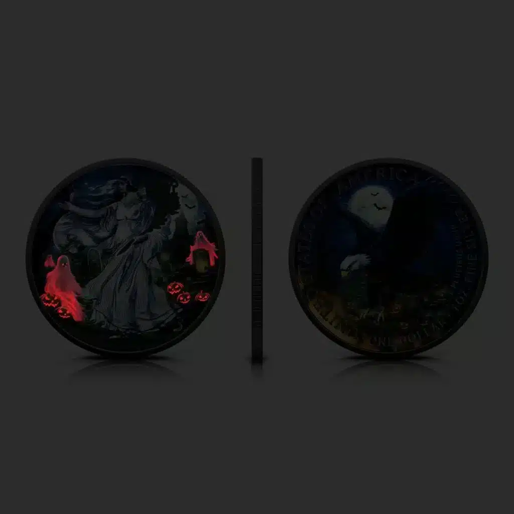 Bajo poca luz, se muestran dos monedas de Halloween USA American Eagle 2024 Noche Fantasma 1 oz Plata BU: la izquierda muestra una mujer con fantasmas y jack-o-lanterns resplandecientes; la derecha muestra un búho y un águila resplandecientes. Entre ellas aparece un canto de moneda.