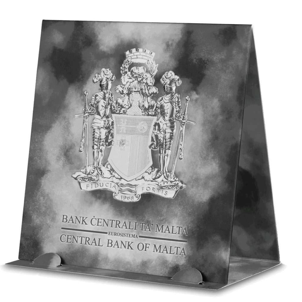Espositore triangolare per la moneta 2023 Cavalieri del Passato 5 Euro 1 oz Argento Fior di Conio, con lo stemma di Malta e la scritta "Bank Ċentrali Ta' Malta Eurosystem Central Bank of Malta" su sfondo grigio nuvoloso.