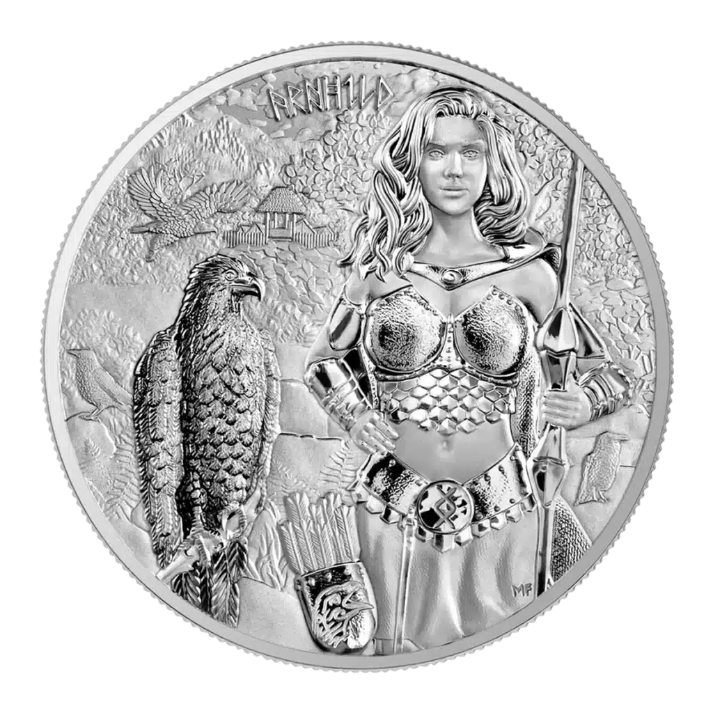 The 2025 Valkyries: Arnhild 1 oz Silver BU features a warrior woman in armor with a spear beside an eagle, arrows and a lion-emblazoned shield at her feet, and mountains, forest, and house in the background.