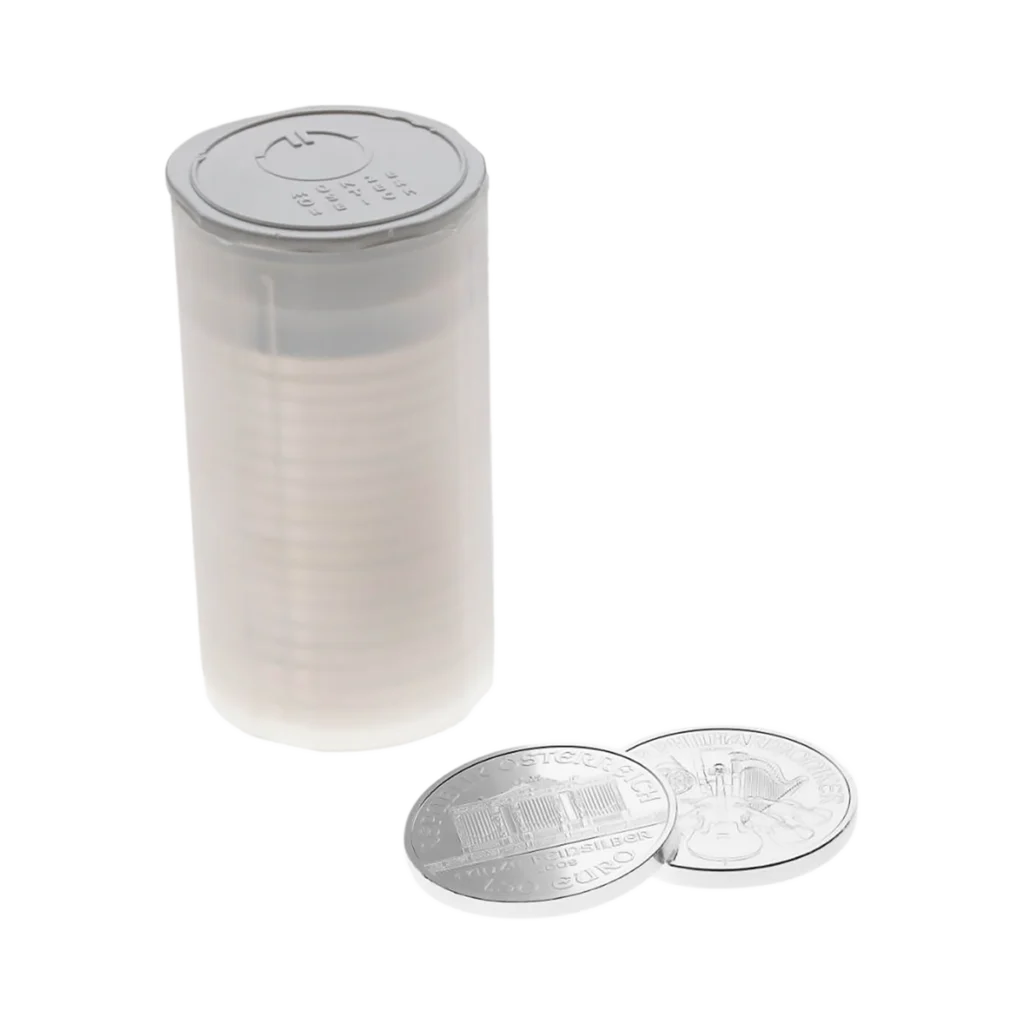 A transparent tube of Silver Vienna Philharmonic coins stands upright, with two silver coins lying flat beside it on a white surface.