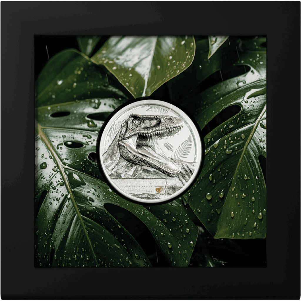 Moneta da collezione "Jurassic Relics – Carcharodontosaurus" Italpreziosi in argento con incisione del Carcharodontosaurus, presentata in confezione da collezione con cornice nera e sfondo con foglie tropicali.