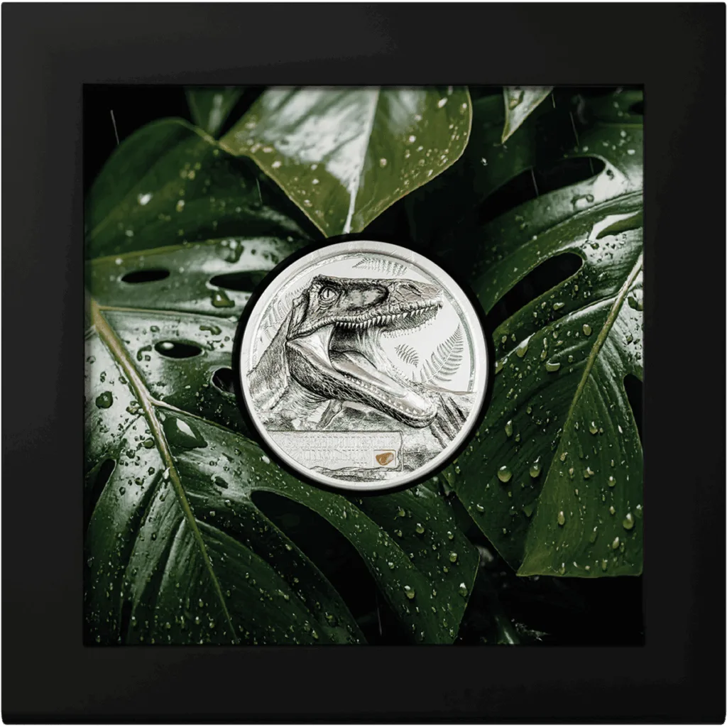 "Jurassic Relics – Carcharodontosaurus" Italpreziosi silver collectible coin featuring a Carcharodontosaurus engraving, presented in a collector's display box with a black frame and a tropical leaves background.