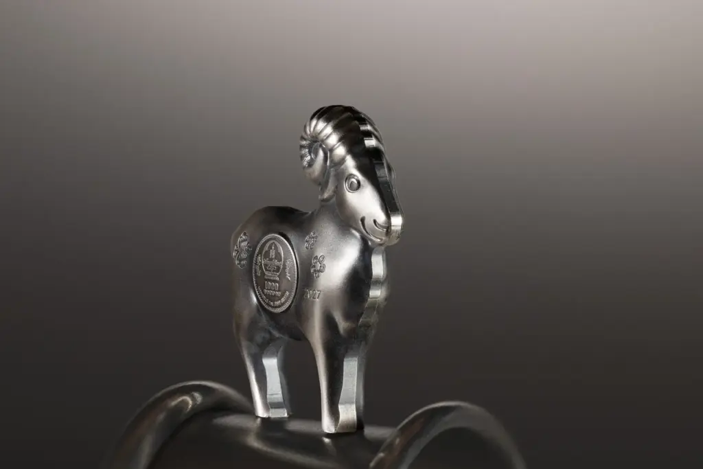 Moneta sagomata Fluffy Silver Sheep 2027 in argento anticato ripresa frontalmente, in equilibrio su un supporto metallico curvo.