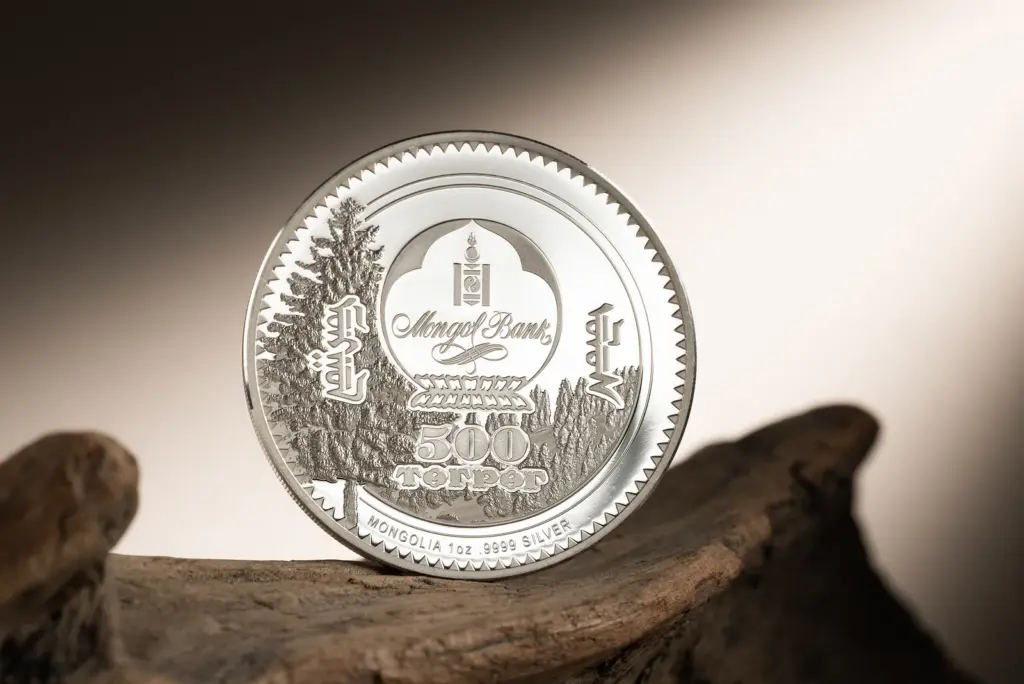 Dritto della moneta Woodland Spirits - Leopardo delle Nevi 1 oz argento con l'emblema della Mongol Bank e il valore 500 Togrog, in piedi su un tronco di legno.