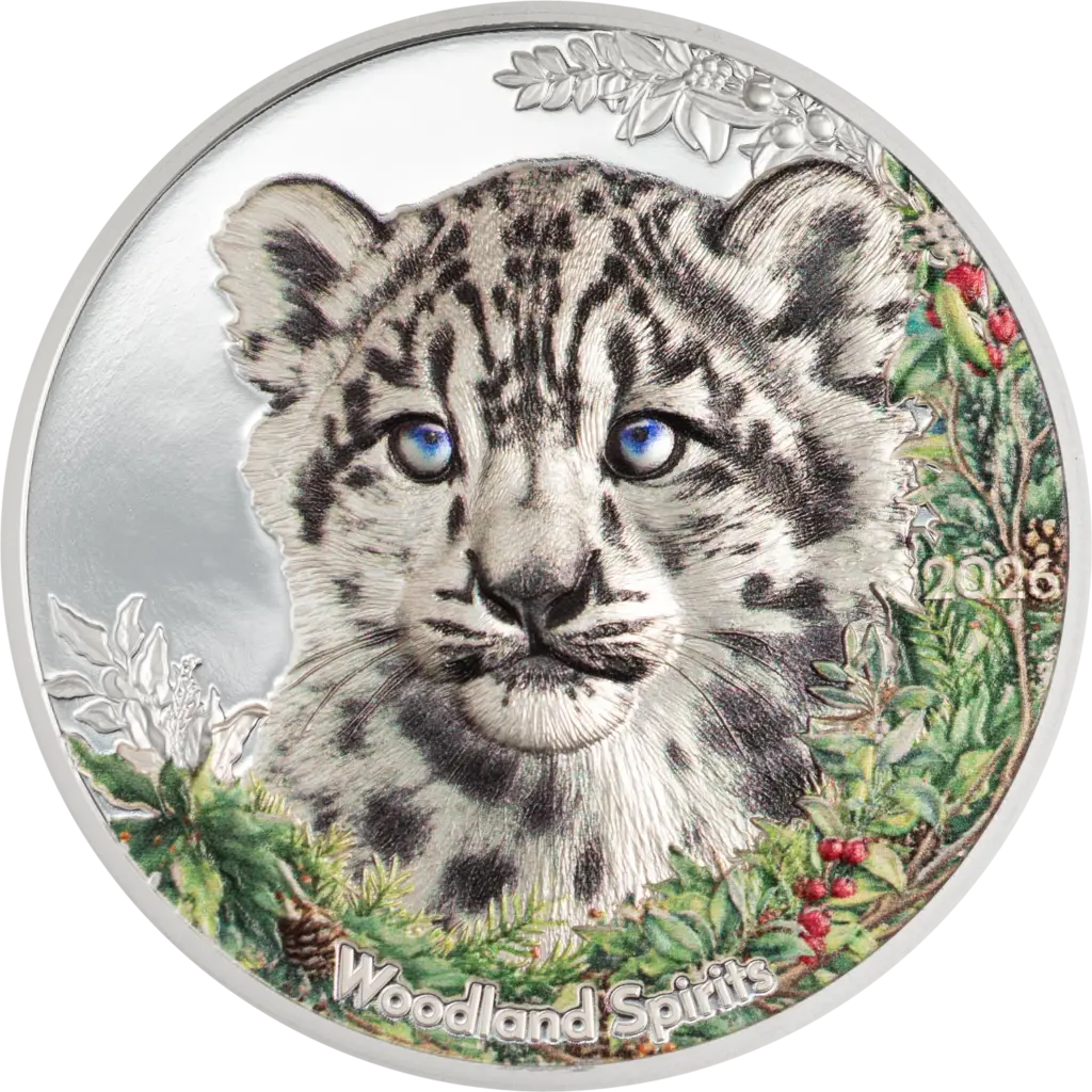 La moneta Woodland Spirits - Leopardo delle Nevi da 1 oz in argento 999.9 proof mostra il muso di un cucciolo di leopardo delle nevi dagli occhi azzurri, circondato da rami di agrifoglio e bacche rosse colorati, con la scritta Woodland Spirits e l'anno 2026.