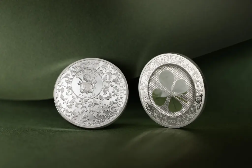 Le due facce della moneta Ounce of Luck 2026 in argento affiancate su drappo verde: a sinistra il dritto con lo stemma delle Isole Cook, a destra il rovescio con il quadrifoglio integrato.