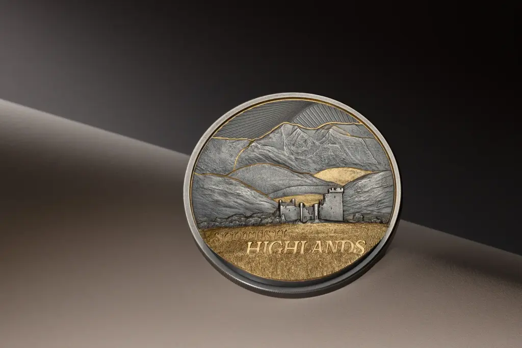 Moneta Golden Landscapes - Scottish Highlands 2 oz argento anticato in piedi su una superficie curva scura, che evidenzia l'ultra alto rilievo del paesaggio e la doratura della brughiera.