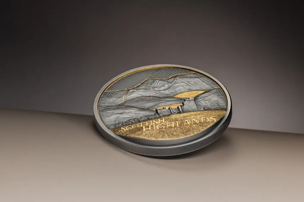 Moneta Golden Landscapes - Scottish Highlands 2 oz argento fotografata quasi di piatto, che mostra lo spessore del tondello e il bordo zigrinato accanto al paesaggio dorato.