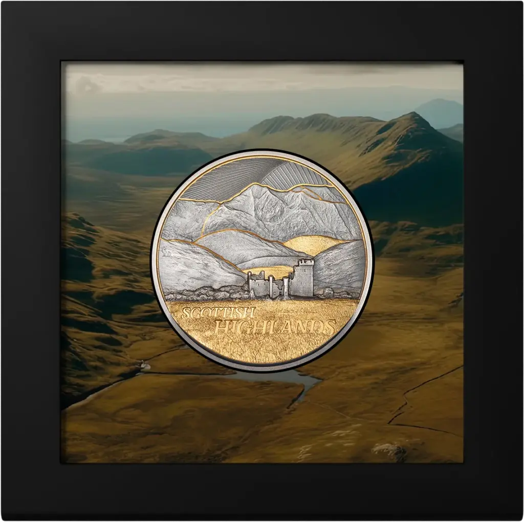 Moneta Golden Landscapes - Scottish Highlands 2 oz argento nella cornice espositiva nera inclusa nella confezione, su una fotografia panoramica delle Highlands scozzesi.