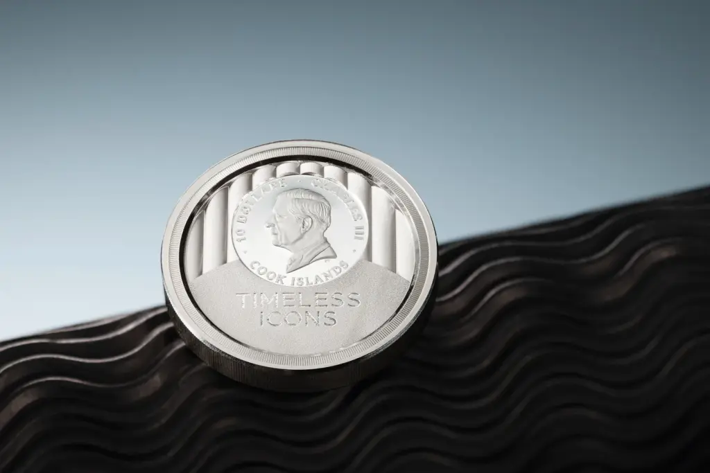 Dritto della moneta Timeless Icons - Statua della Liberta 2 oz argento con il medaglione di re Carlo III e la scritta TIMELESS ICONS, appoggiato su una superficie ondulata scura.
