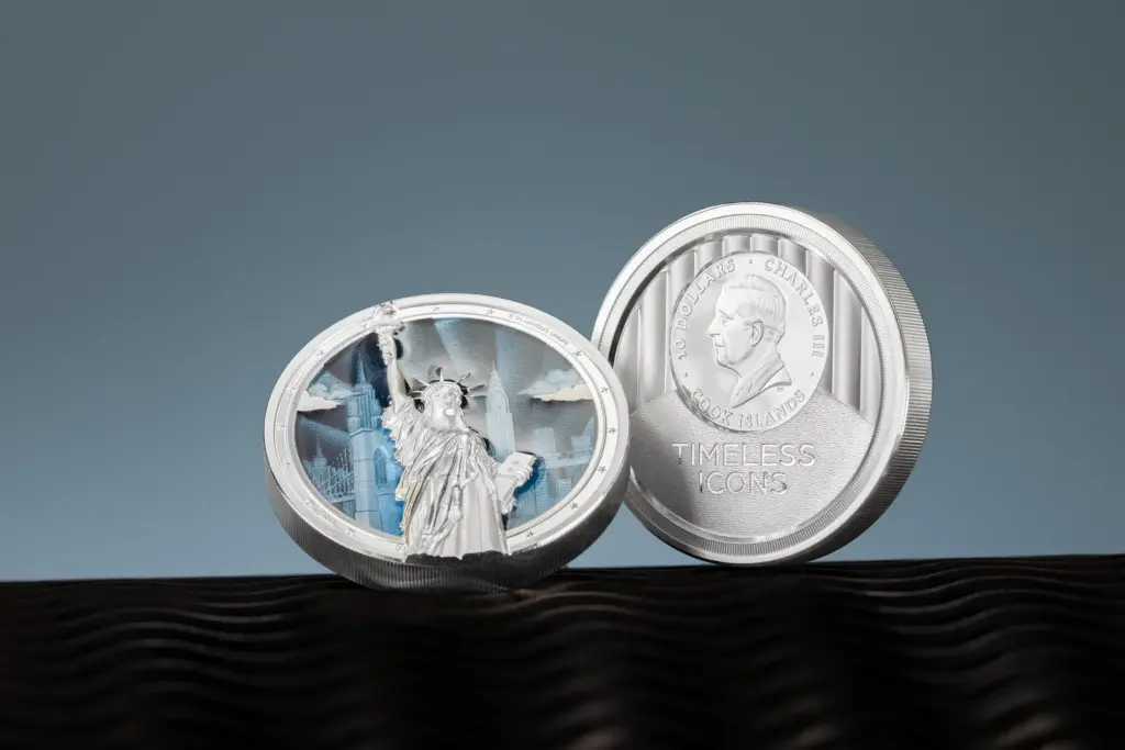 Le due facce della moneta Timeless Icons - Statua della Liberta 2 oz argento affiancate: a sinistra il rovescio con la statua in altorilievo su smalto blu, a destra il dritto con l'effigie di re Carlo III.