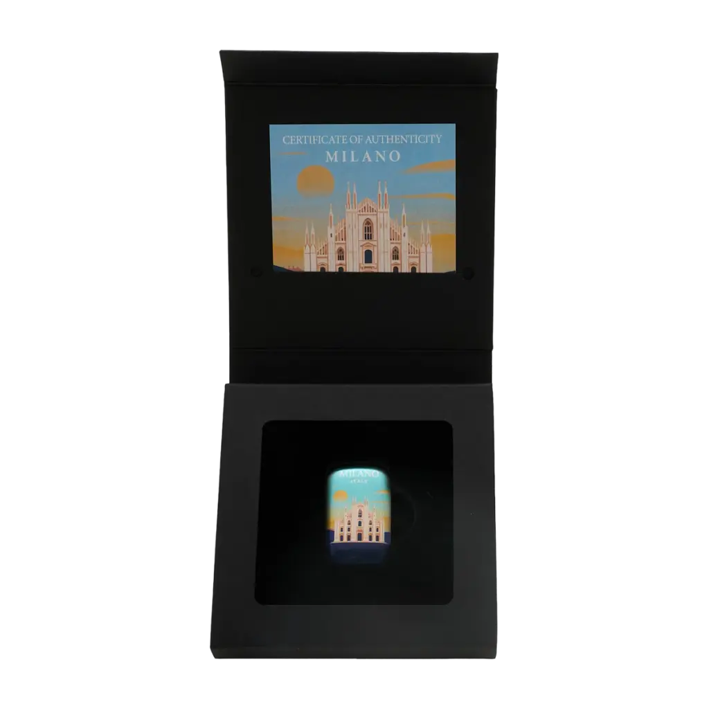 Lingotto Grandi Città Milano nel cofanetto nero aperto incluso nella confezione: il lingotto nell'alloggiamento sagomato e, nel coperchio, l'illustrazione della facciata del Duomo con la scritta CERTIFICATE OF AUTHENTICITY - MILANO.